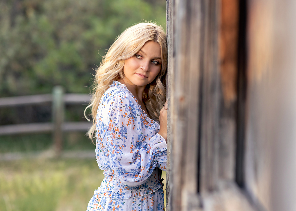 teen with gorgeous blonde hair leaning against a vintage barn for senior pictures 